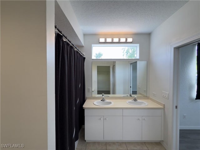 bathroom with double vanity, tile patterned flooring, a textured ceiling, and a sink