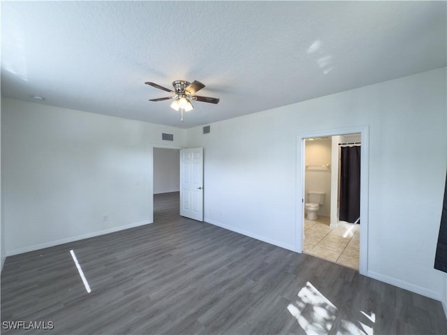 unfurnished bedroom featuring visible vents, baseboards, a textured ceiling, and wood finished floors