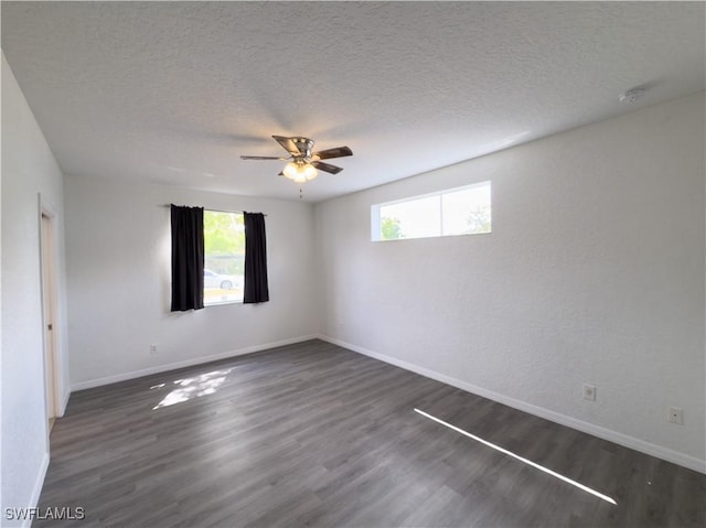 spare room with baseboards, a ceiling fan, dark wood-style flooring, and a textured ceiling