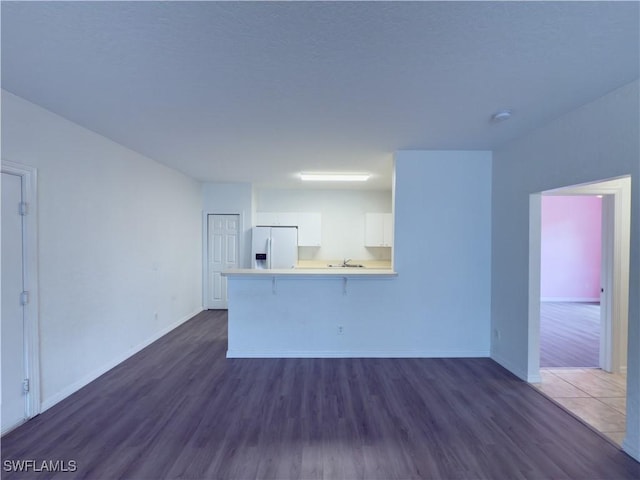 unfurnished living room with dark wood finished floors, baseboards, and a sink