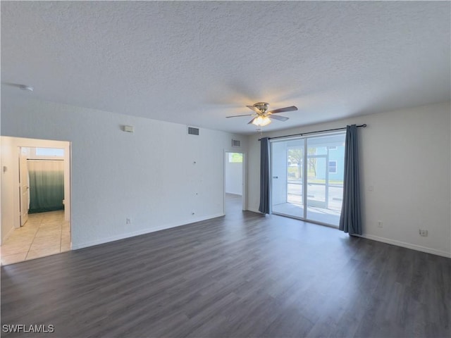 empty room featuring wood finished floors, a ceiling fan, visible vents, and a textured ceiling