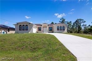 view of front facade with a garage, concrete driveway, and a front yard