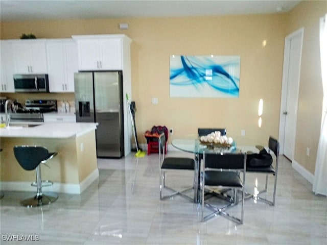 kitchen with light countertops, white cabinets, a breakfast bar area, and appliances with stainless steel finishes