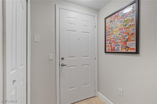 doorway to outside featuring light tile patterned floors and baseboards