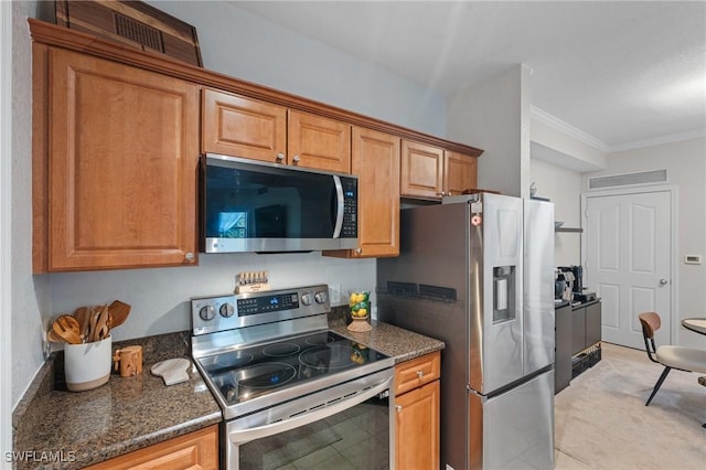 kitchen with brown cabinetry, dark stone counters, appliances with stainless steel finishes, and crown molding