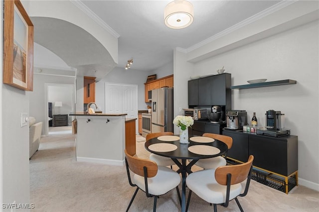 dining room featuring ornamental molding, baseboards, and light carpet