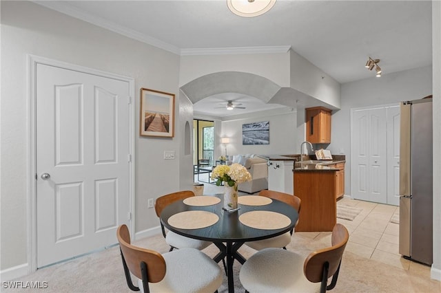 dining space with ornamental molding, arched walkways, light tile patterned floors, baseboards, and ceiling fan