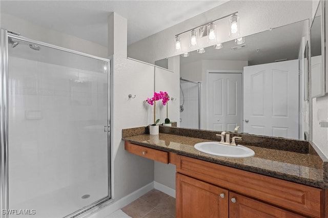 full bath with baseboards, vanity, a shower stall, and tile patterned flooring