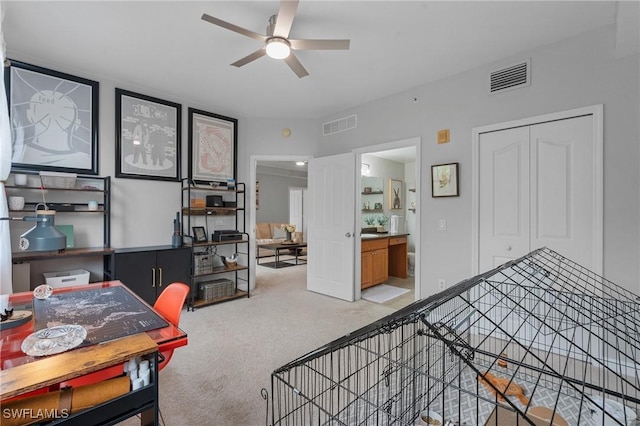 carpeted bedroom with ceiling fan, visible vents, and ensuite bath