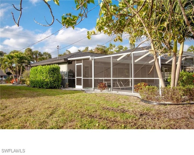 rear view of house with a lanai and a lawn