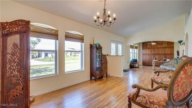 living area featuring vaulted ceiling, baseboards, light wood-type flooring, and arched walkways