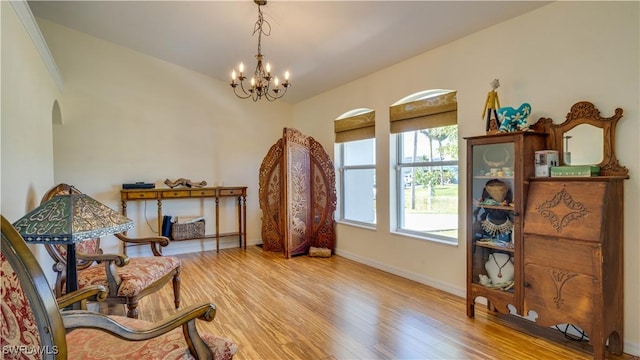 sitting room featuring an inviting chandelier, wood finished floors, arched walkways, and baseboards