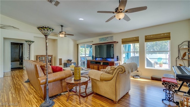 living room featuring light wood finished floors, visible vents, baseboards, and a ceiling fan