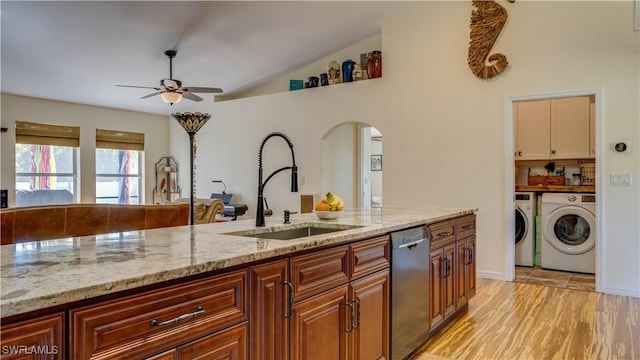 kitchen with independent washer and dryer, a sink, stainless steel dishwasher, arched walkways, and ceiling fan