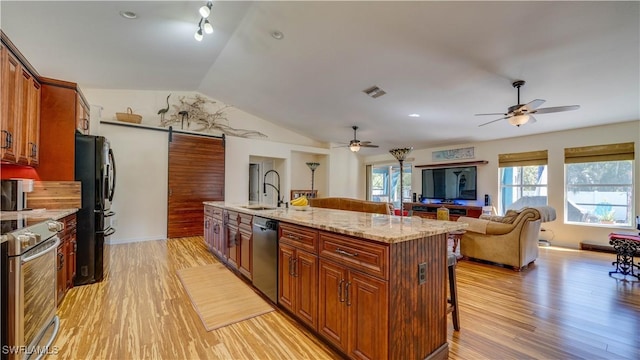 kitchen featuring visible vents, ceiling fan, vaulted ceiling, a kitchen breakfast bar, and stainless steel appliances