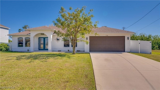 view of front of home with stucco siding, driveway, french doors, a front yard, and a garage