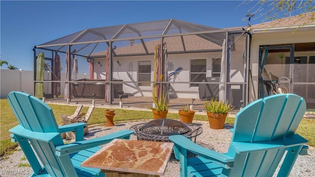 view of patio / terrace with glass enclosure, fence, outdoor dining space, and an outdoor fire pit