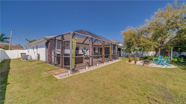 rear view of house featuring a fire pit, glass enclosure, a yard, a fenced backyard, and a patio