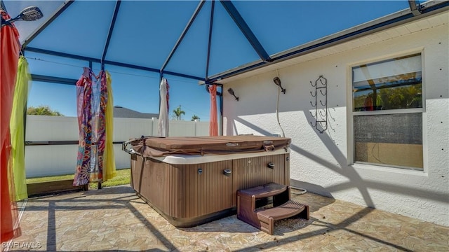 view of patio featuring glass enclosure, fence, and a hot tub