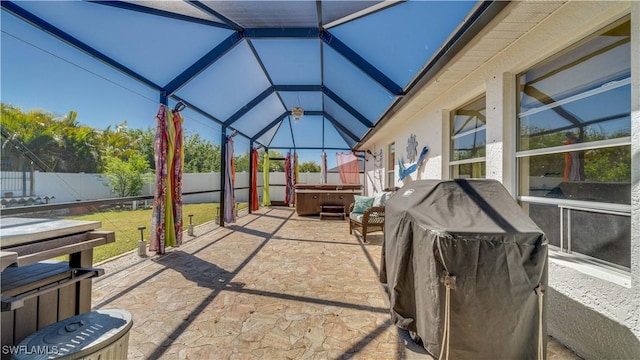 view of patio featuring area for grilling, glass enclosure, a hot tub, and a fenced backyard