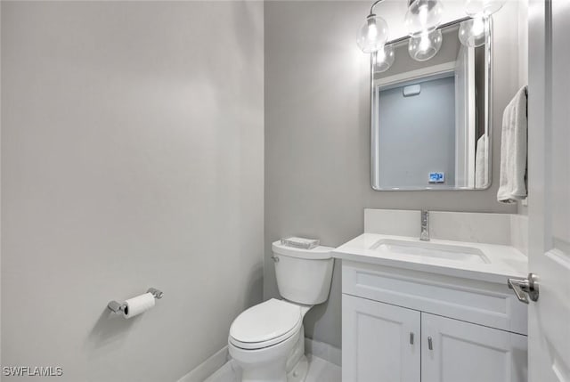 half bath with vanity, toilet, and baseboards