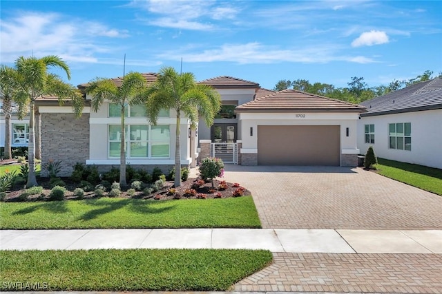 view of front of property with stone siding, stucco siding, an attached garage, and decorative driveway