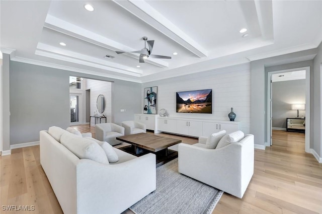 living room with light wood finished floors, baseboards, and a tray ceiling