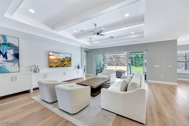 living room with a raised ceiling and light wood-style floors