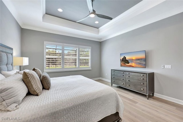 bedroom with a tray ceiling, baseboards, and light wood-style floors