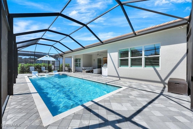 outdoor pool featuring glass enclosure, a patio, an outdoor hangout area, and ceiling fan