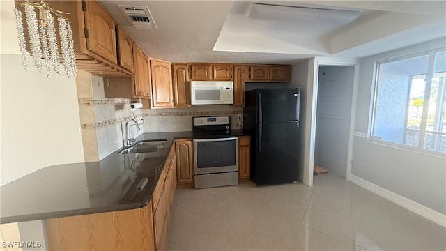 2510 SE 16th Pl Unit 103, Cape Coral, FL 33904 - kitchen with stainless steel electric stove, freestanding refrigerator, a sink, white microwave, and dark countertops