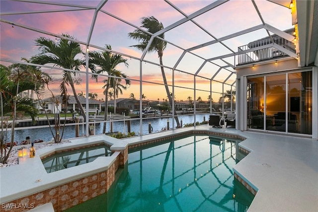 view of swimming pool with a lanai, a water view, and a pool with connected hot tub