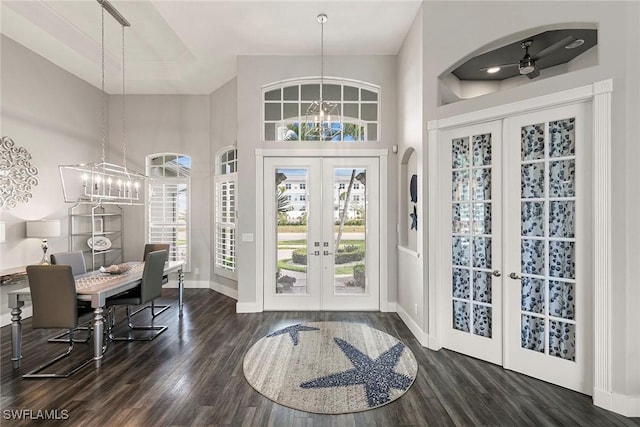 entryway with wood finished floors, baseboards, an inviting chandelier, arched walkways, and french doors