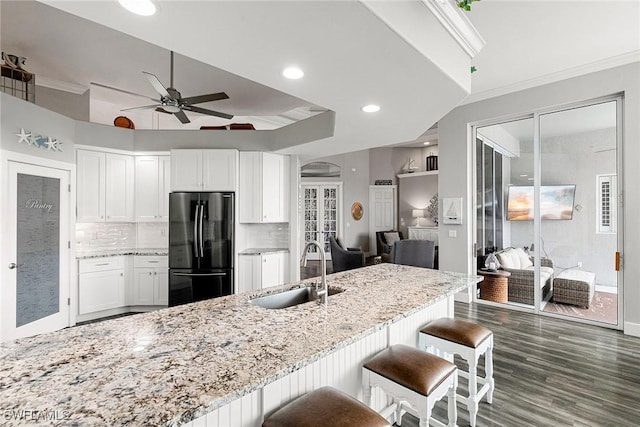 kitchen with white cabinets, light stone countertops, freestanding refrigerator, and a sink