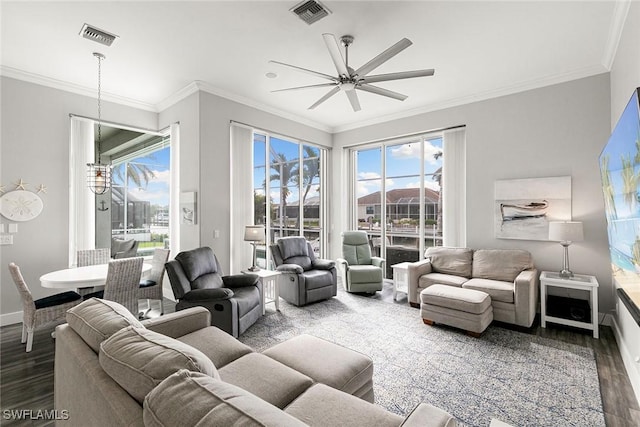 living room featuring visible vents, ornamental molding, baseboards, and wood finished floors