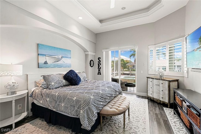 bedroom featuring access to exterior, baseboards, recessed lighting, wood finished floors, and a raised ceiling