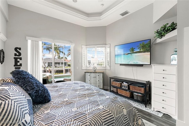 bedroom featuring visible vents, a tray ceiling, wood finished floors, crown molding, and access to exterior