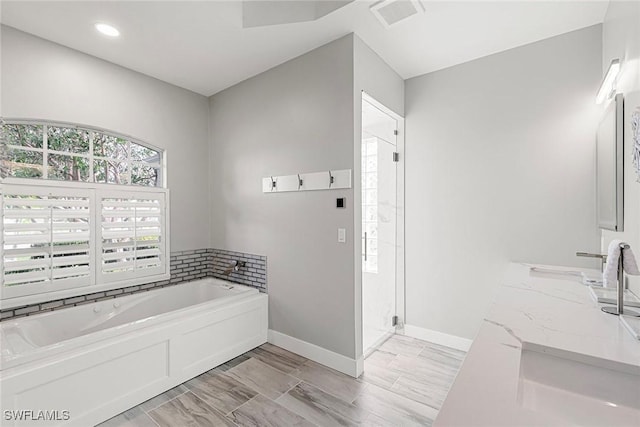 bathroom with visible vents, a shower stall, baseboards, a garden tub, and vanity