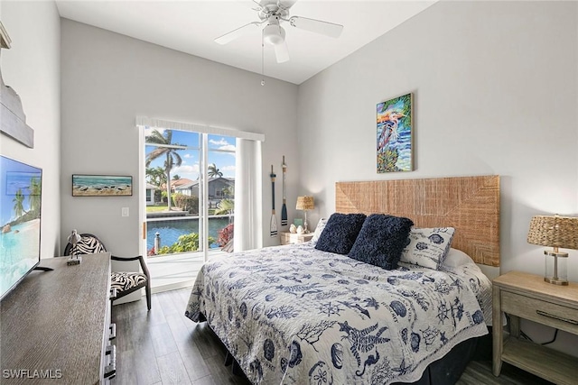 bedroom with a water view, wood finished floors, and a ceiling fan