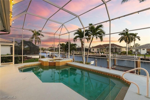 pool at dusk with a water view, a patio, a lanai, and a pool with connected hot tub