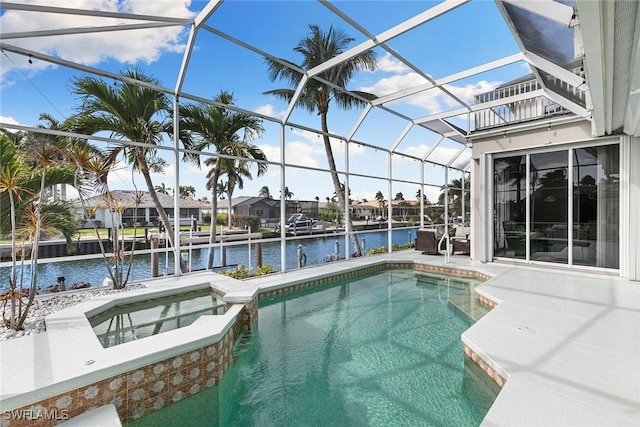 view of swimming pool with glass enclosure, a dock, a pool with connected hot tub, a water view, and a patio area