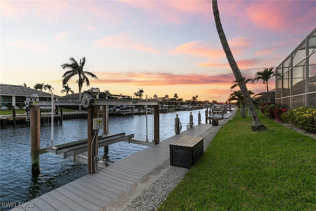 view of dock featuring a yard, a water view, and boat lift