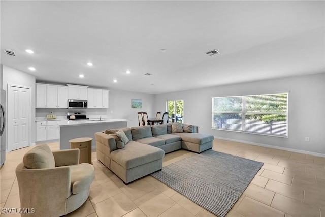 living room with light tile patterned floors, recessed lighting, visible vents, and baseboards