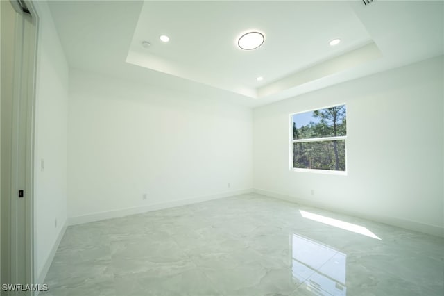 unfurnished room with recessed lighting, baseboards, and a raised ceiling