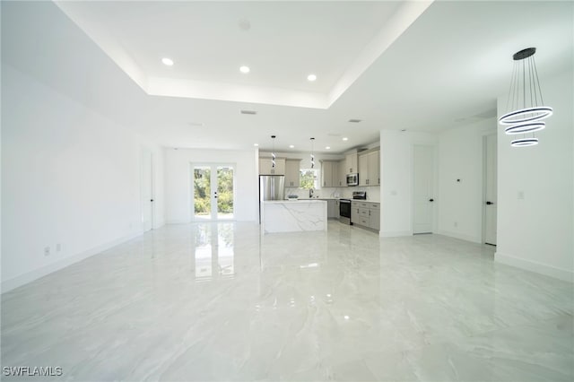 unfurnished living room with baseboards, a tray ceiling, recessed lighting, french doors, and marble finish floor