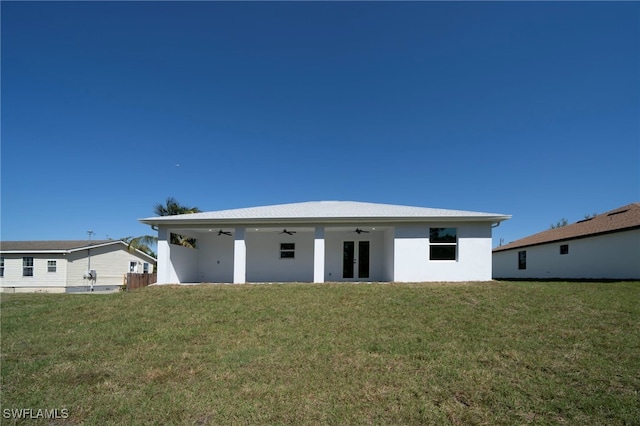 back of house featuring ceiling fan, french doors, a yard, and stucco siding