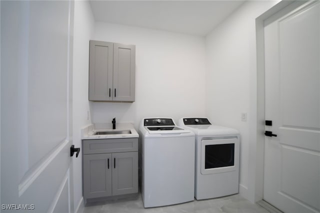 laundry room with cabinet space, separate washer and dryer, and a sink