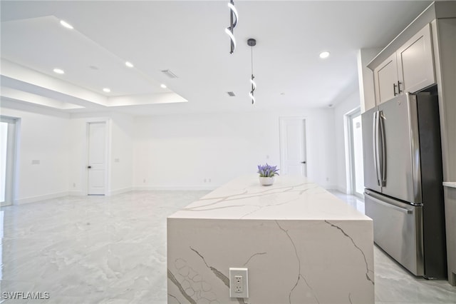 kitchen with marble finish floor, a tray ceiling, a kitchen island, open floor plan, and freestanding refrigerator