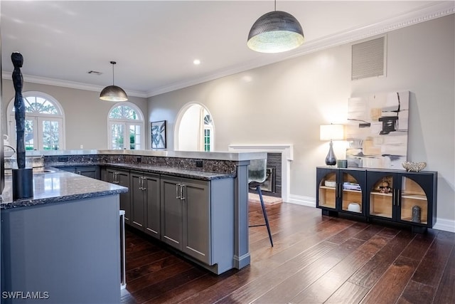 13189 Valewood Dr, Naples, FL 34119 - kitchen featuring a breakfast bar area, dark wood-style floors, dark stone countertops, crown molding, and a fireplace
