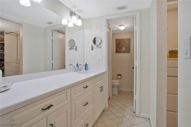 full bathroom with vanity, baseboards, visible vents, tile patterned flooring, and toilet